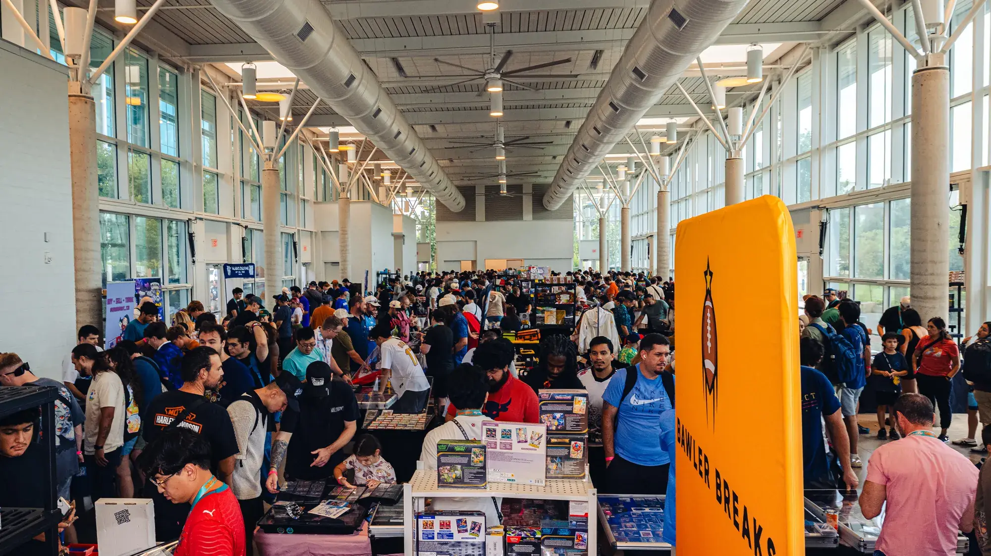 A packed hall of collectors browsing card tables at a Mom and Pop Card Show, with a Bawler Breaks banner standing above the floor